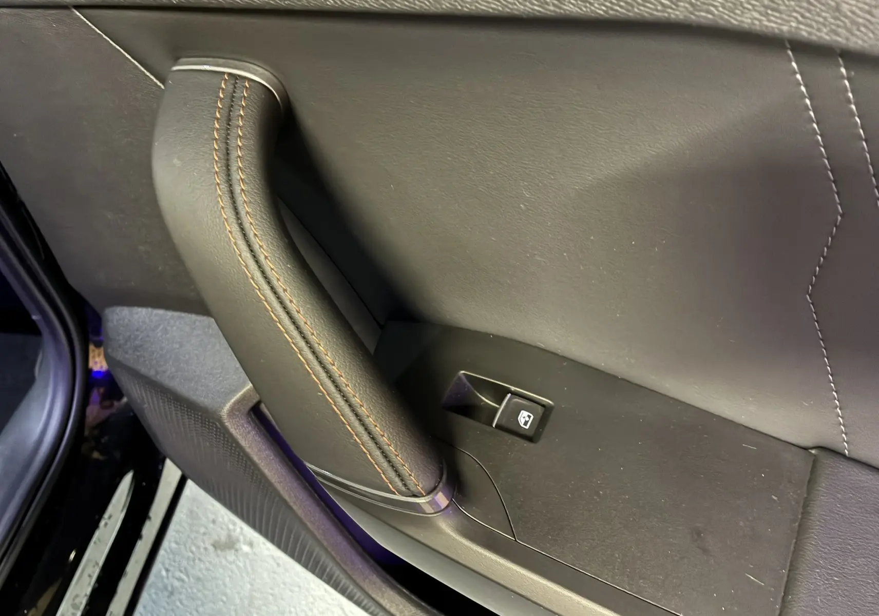 Détail de la poignée intérieure en cuir noir avec surpiqûres marron sur la porte côté gauche d'une CUPRA Formentor 1.4 e-HYBRID 2023.