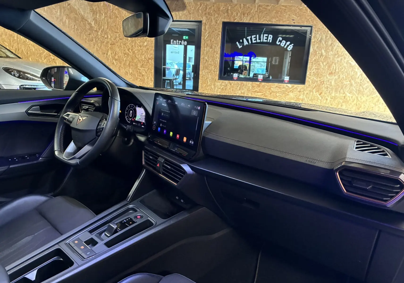 Vue intérieure côté conducteur du tableau de bord noir du CUPRA Formentor 1.4 E-HYBRID avec écran tactile central allumé.