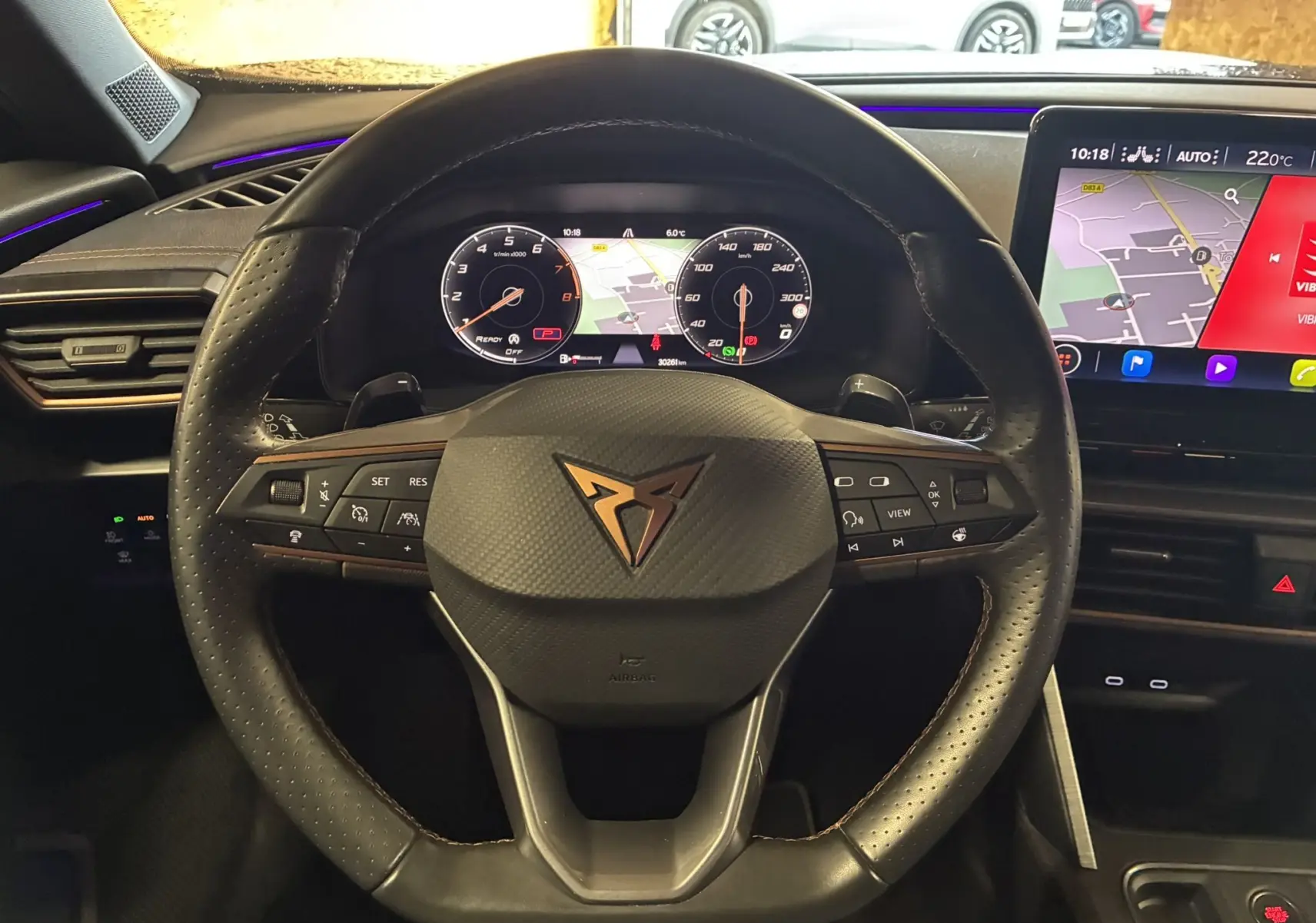 Vue rapprochée du volant noir perforé de la CUPRA Formentor 1.4 E-HYBRID 2023 avec tableau de bord numérique et écran tactile.