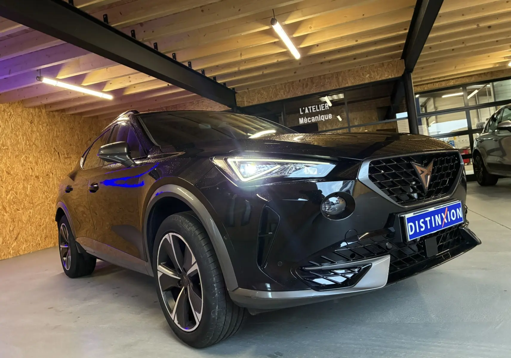 Vue 3/4 avant gauche du CUPRA Formentor noir 2023 avec calandre distinctive et phares LED allumés en intérieur.