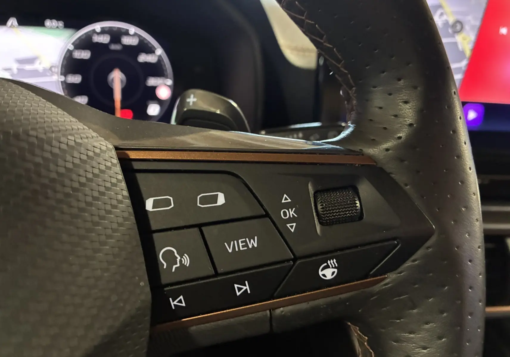 Gros plan sur les commandes au volant en cuir noir perforé du CUPRA Formentor 1.4 E-HYBRID 2023, avec touches fonctionnelles visibles.