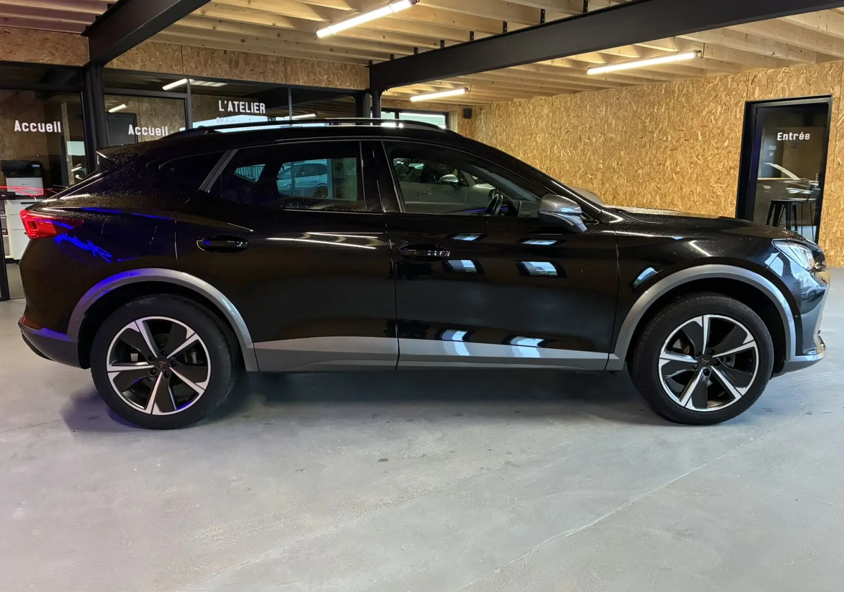 Vue de profil côté gauche d’un CUPRA Formentor noir 2023 hybride rechargeable, avec jantes alliage et détails gris sur les passages de roues.