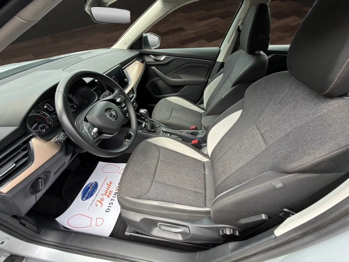 Intérieur avant droit du Skoda Kamiq gris clair 2023, sièges tissu bicolore et tableau de bord avec écran tactile.
