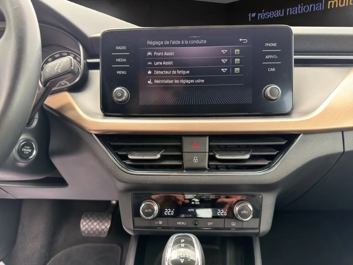 Tableau de bord et console centrale du Skoda Kamiq 2023 avec écran tactile, climatisation digitale et bouton start/stop.