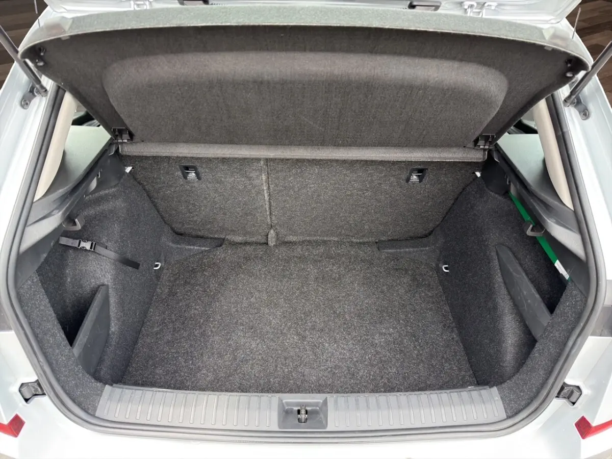 Coffre ouvert vu de l'arrière d'un Skoda Kamiq gris clair 2023 avec intérieur de coffre en tissu gris.
