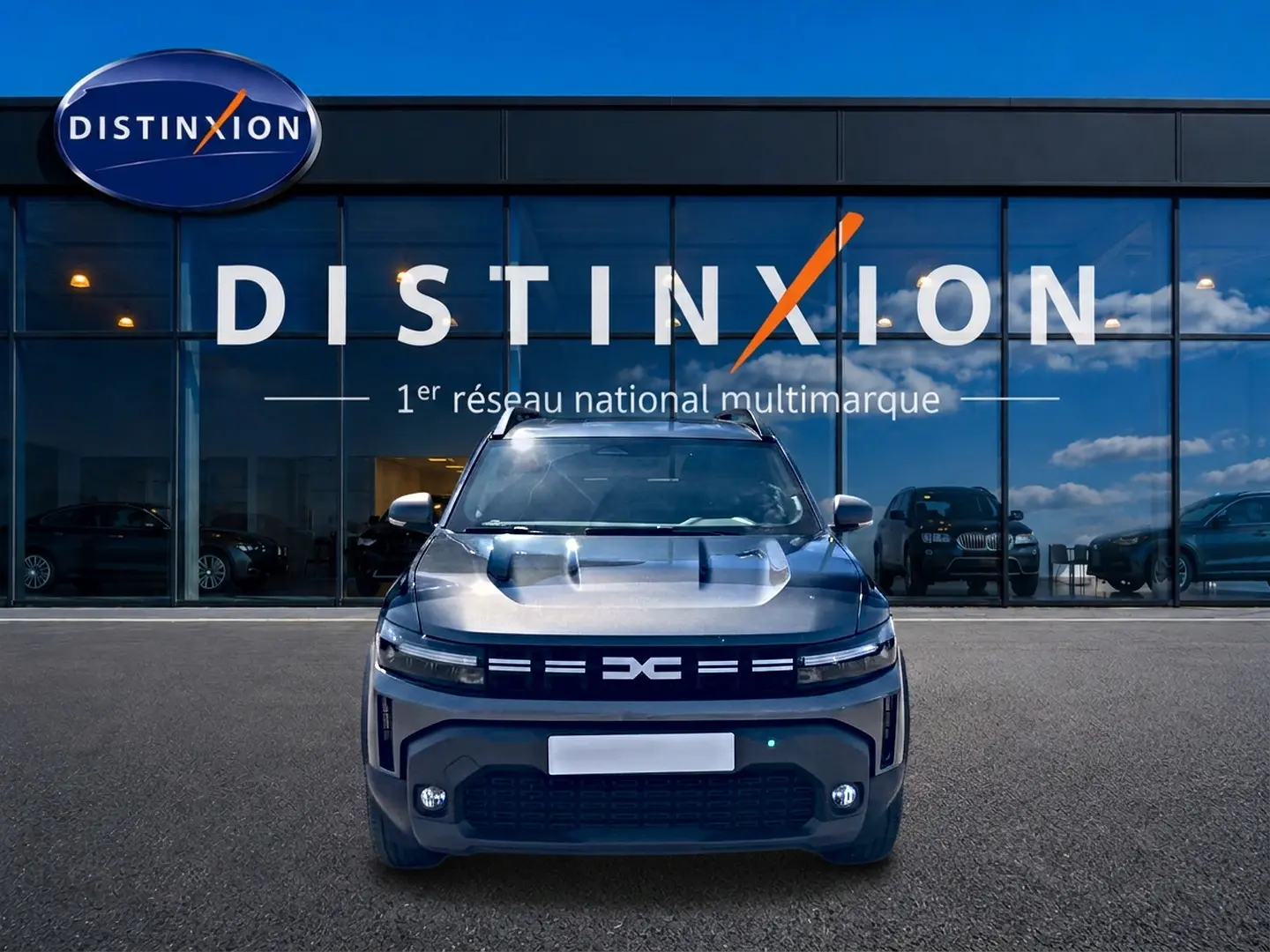 Vue frontale du Dacia Duster 1.2 mild hybrid 140 Journey gris schiste, avec calandre distinctive et phares LED allumés.