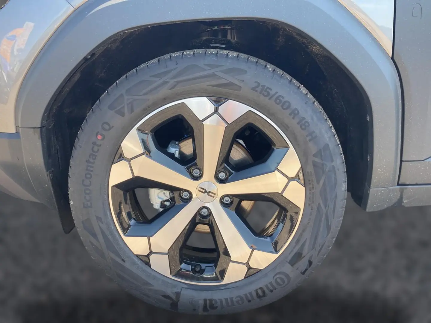 Gros plan sur la roue avant droite du Dacia Duster gris schiste avec jante alliage 18 pouces au design géométrique.