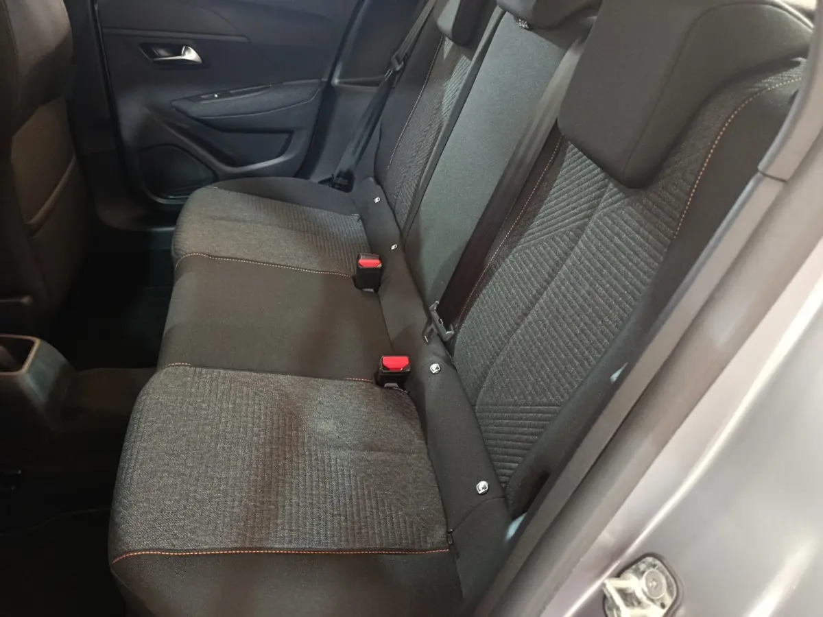 Vue côté droit de la banquette arrière grise avec surpiqûres orange dans une Peugeot 208 Hybrid 2025.