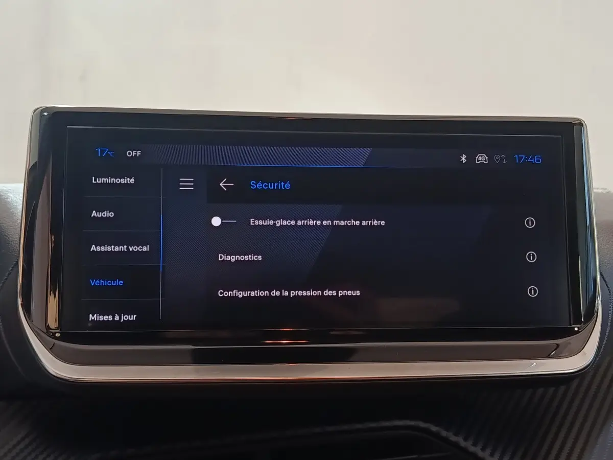 Écran tactile central de la Peugeot 208 Hybrid gris clair affichant le menu sécurité avec options essuie-glace et diagnostics.