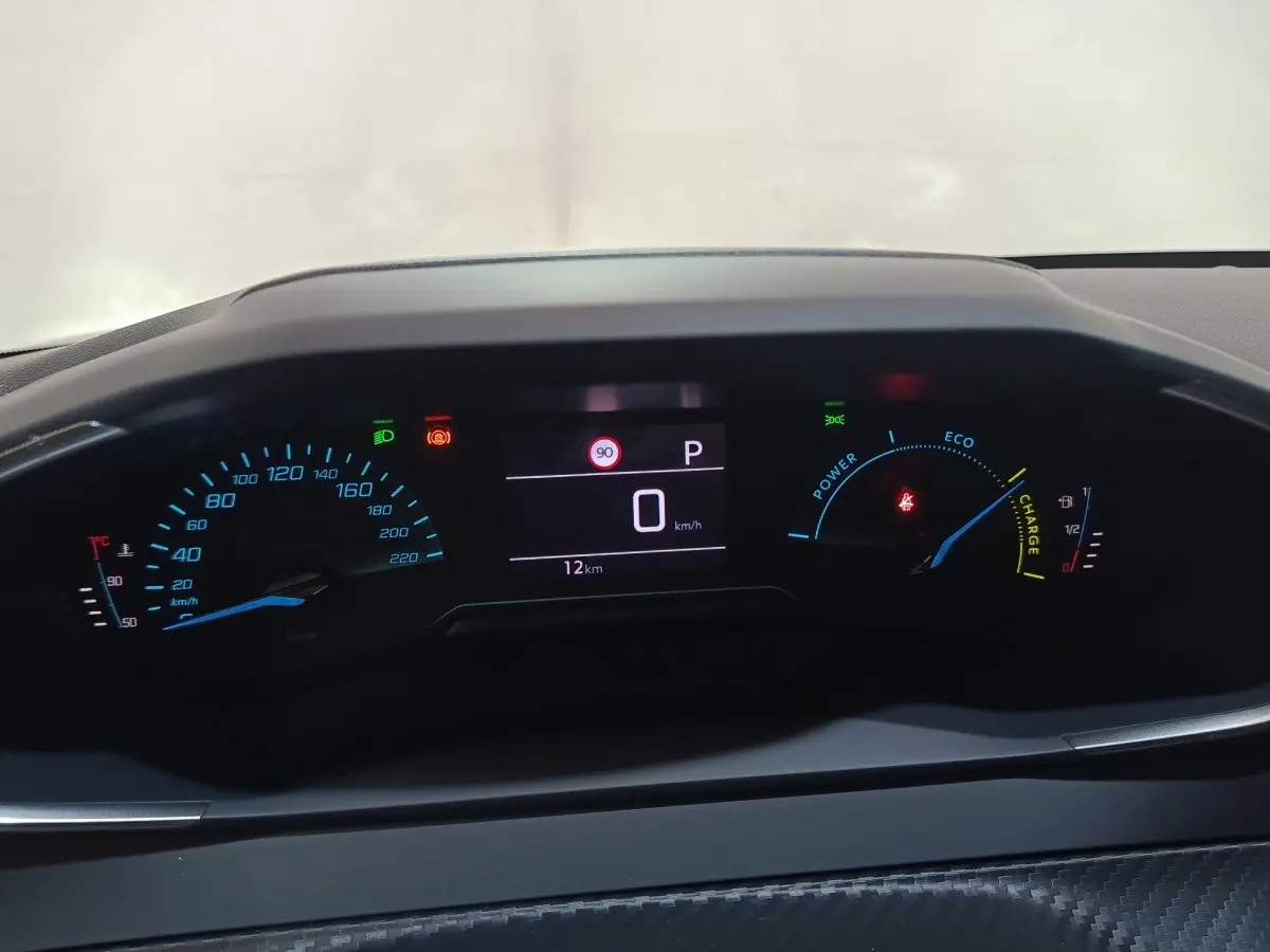 Vue rapprochée du combiné d'instruments numérique de la Peugeot 208 Hybrid 2025, affichage vitesse et indicateurs hybrides.