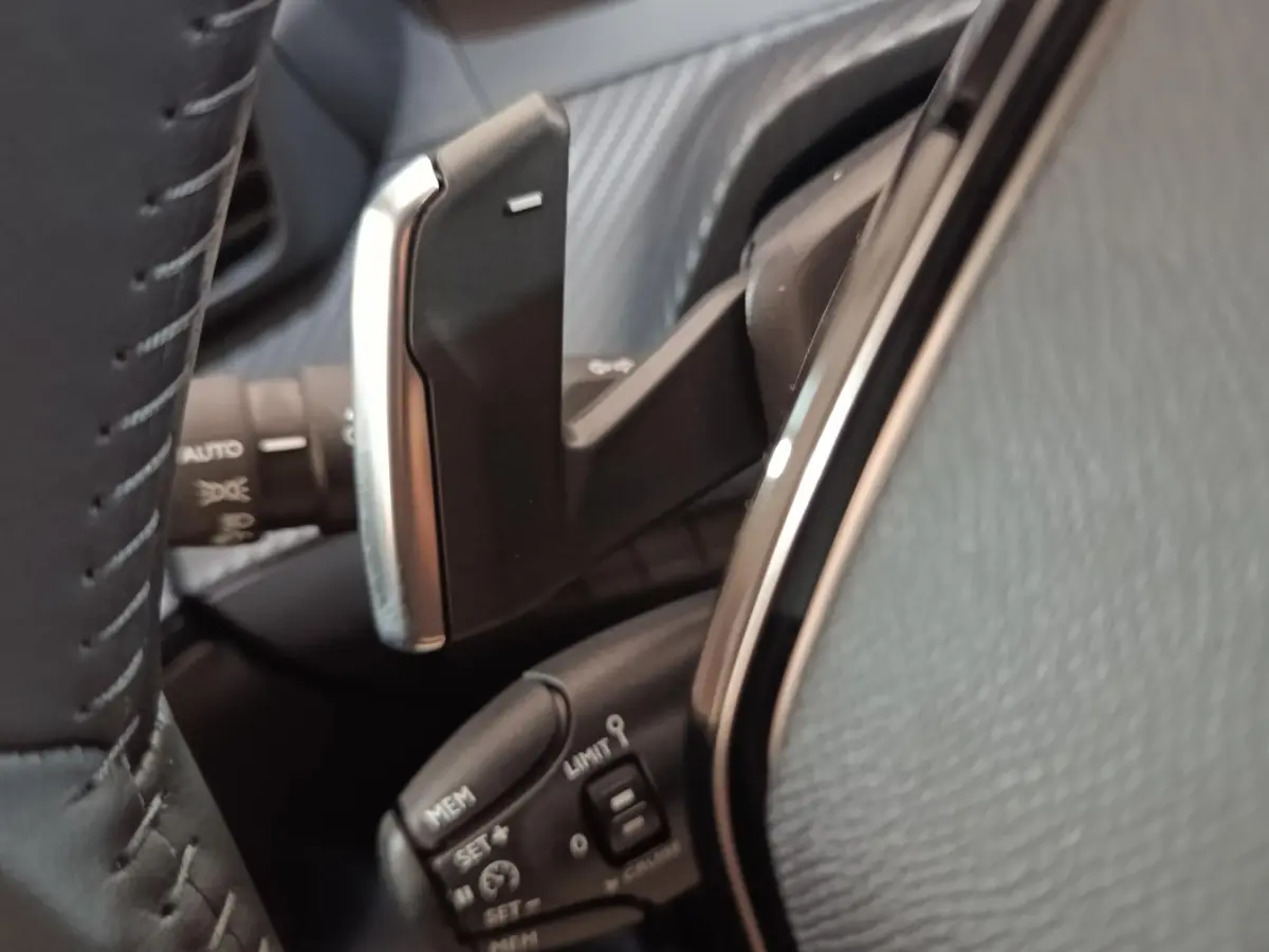Gros plan sur la commande au volant cuir de la Peugeot 208 Hybrid 100 e-DCS6 Style gris clair, avec boutons multifonctions.