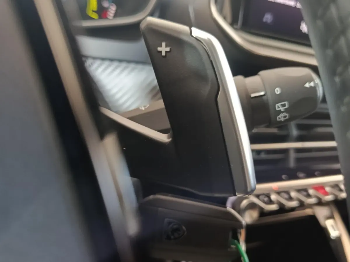 Gros plan sur la palette de changement de vitesse côté droit du volant dans l’habitacle d’une Peugeot 208 gris clair.