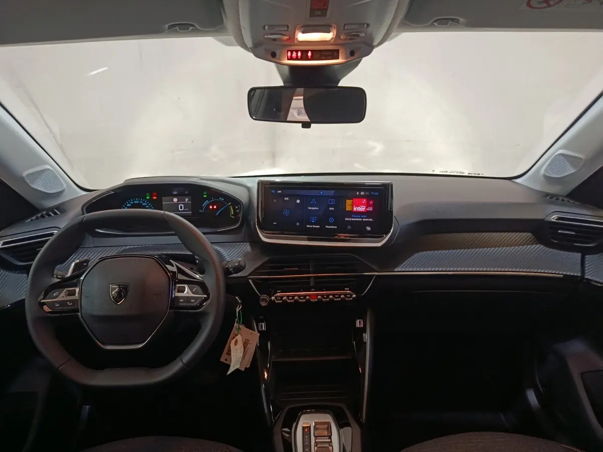 Vue intérieure avant du tableau de bord gris clair de la Peugeot 208 Hybrid avec écran tactile et volant multifonctions cuir.