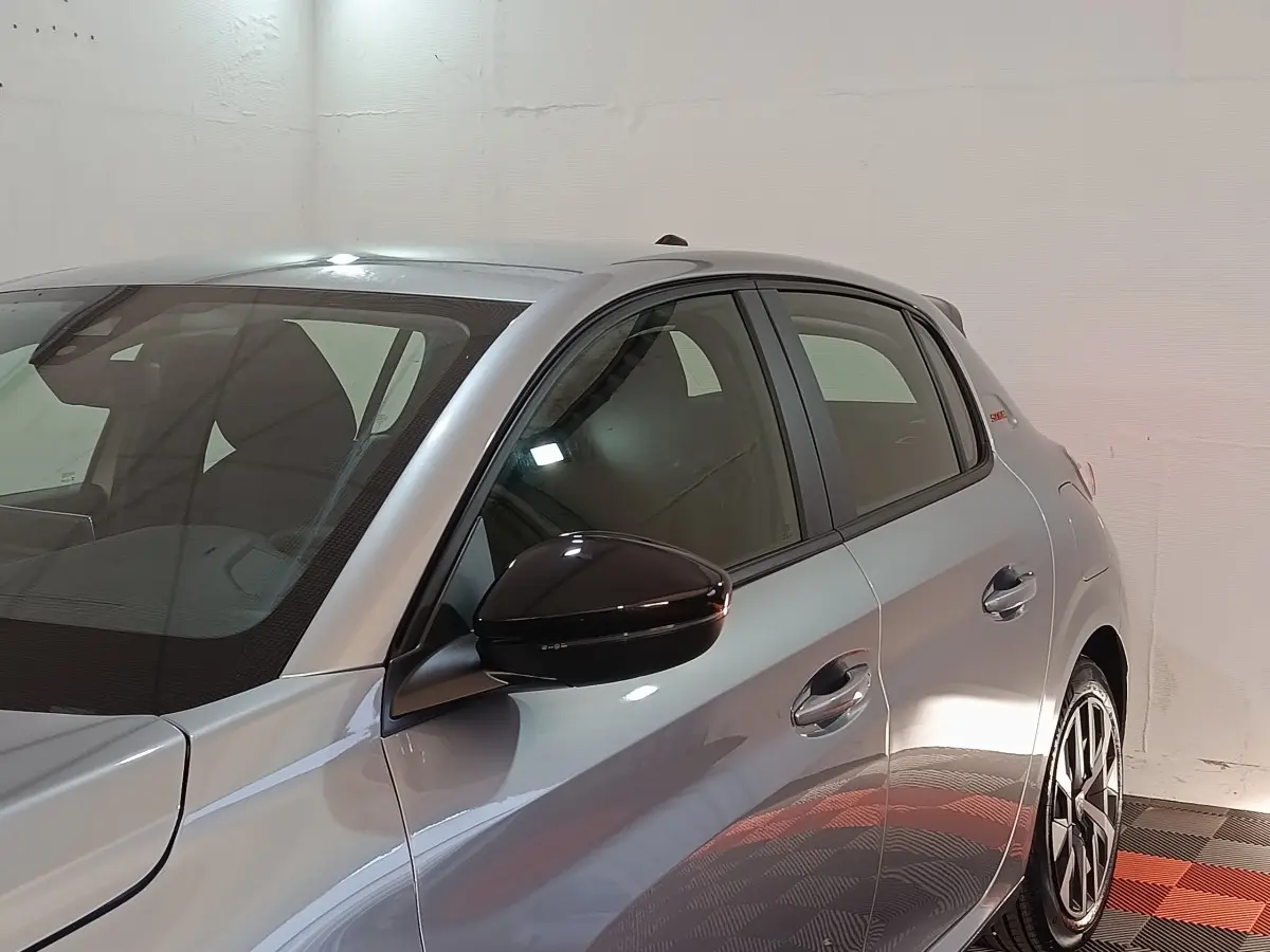 Vue latérale droite d'une Peugeot 208 Hybrid 100 e-DCS6 Style gris clair avec rétroviseur noir brillant.