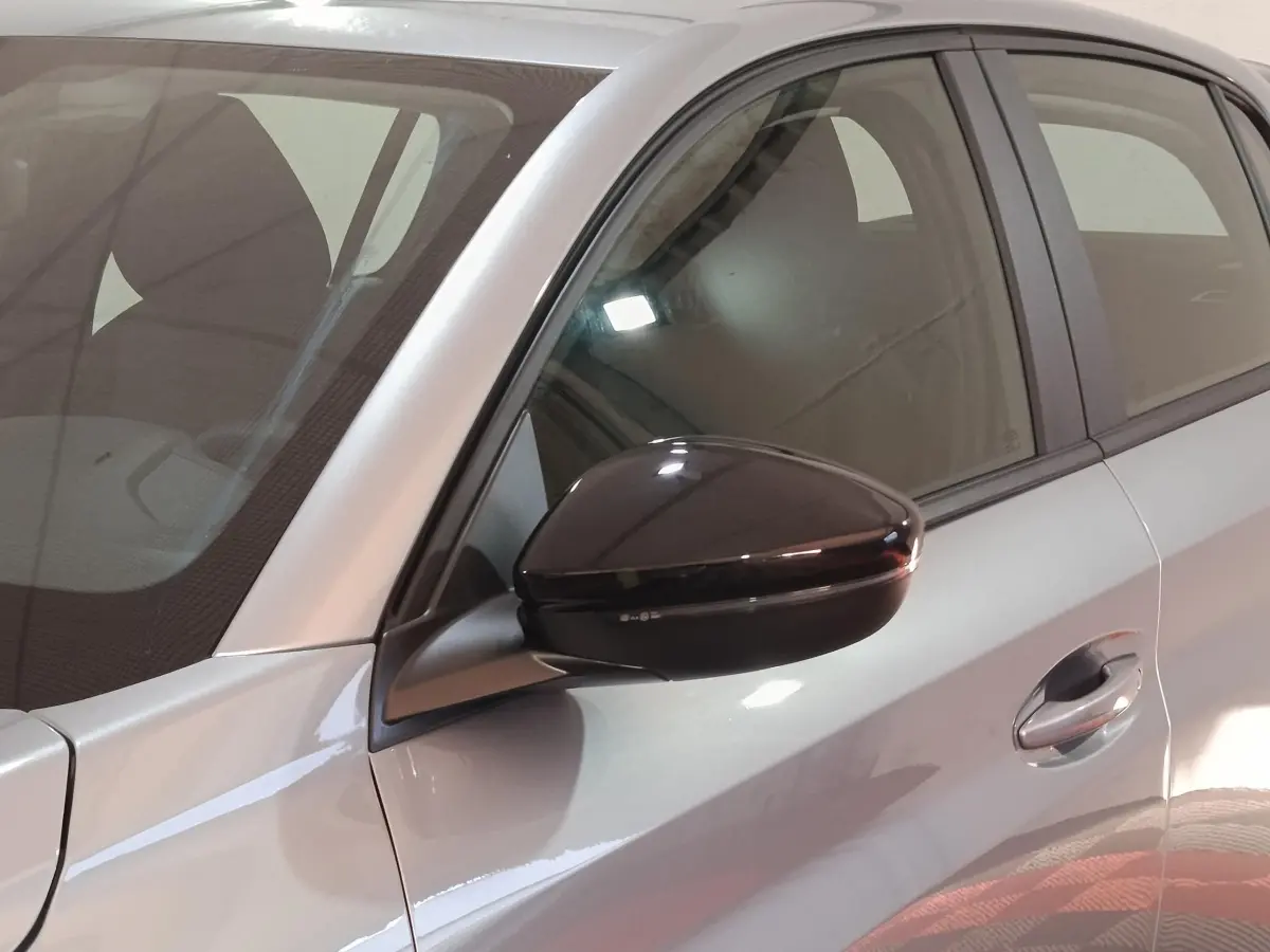 Gros plan sur le rétroviseur noir et la portière côté conducteur d’une Peugeot 208 Hybrid gris clair.