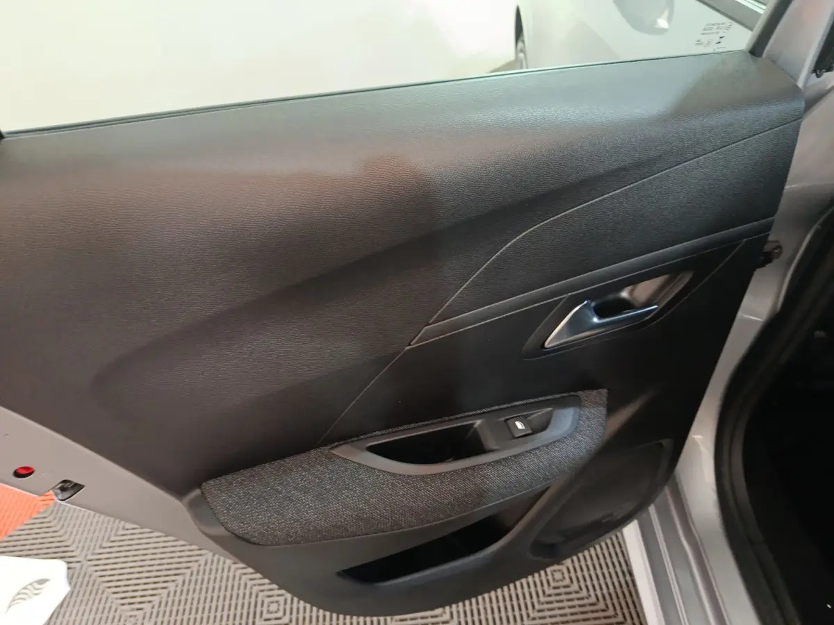 Vue rapprochée de la porte arrière droite gris clair du Peugeot 208 Hybrid 2025 avec habillage noir et commande de vitre.