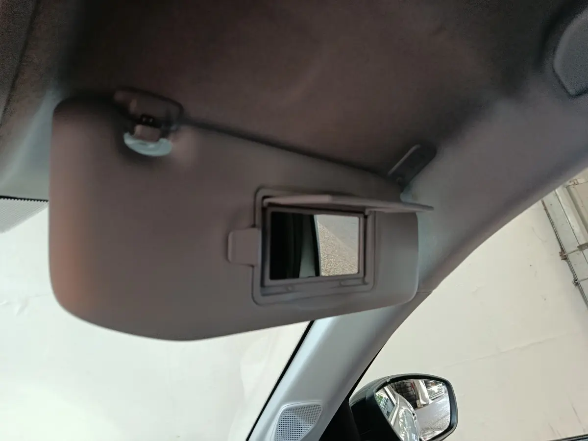 Détail du pare-soleil avec miroir de courtoisie ouvert dans l’habitacle gris clair d’une Peugeot 208 Hybrid 2025.