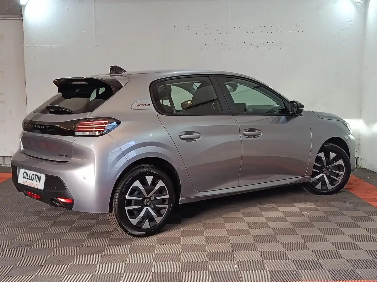 Peugeot 208 Hybrid gris clair vue 3/4 arrière droit, avec jantes stylisées et logo Style sur l'aile arrière.