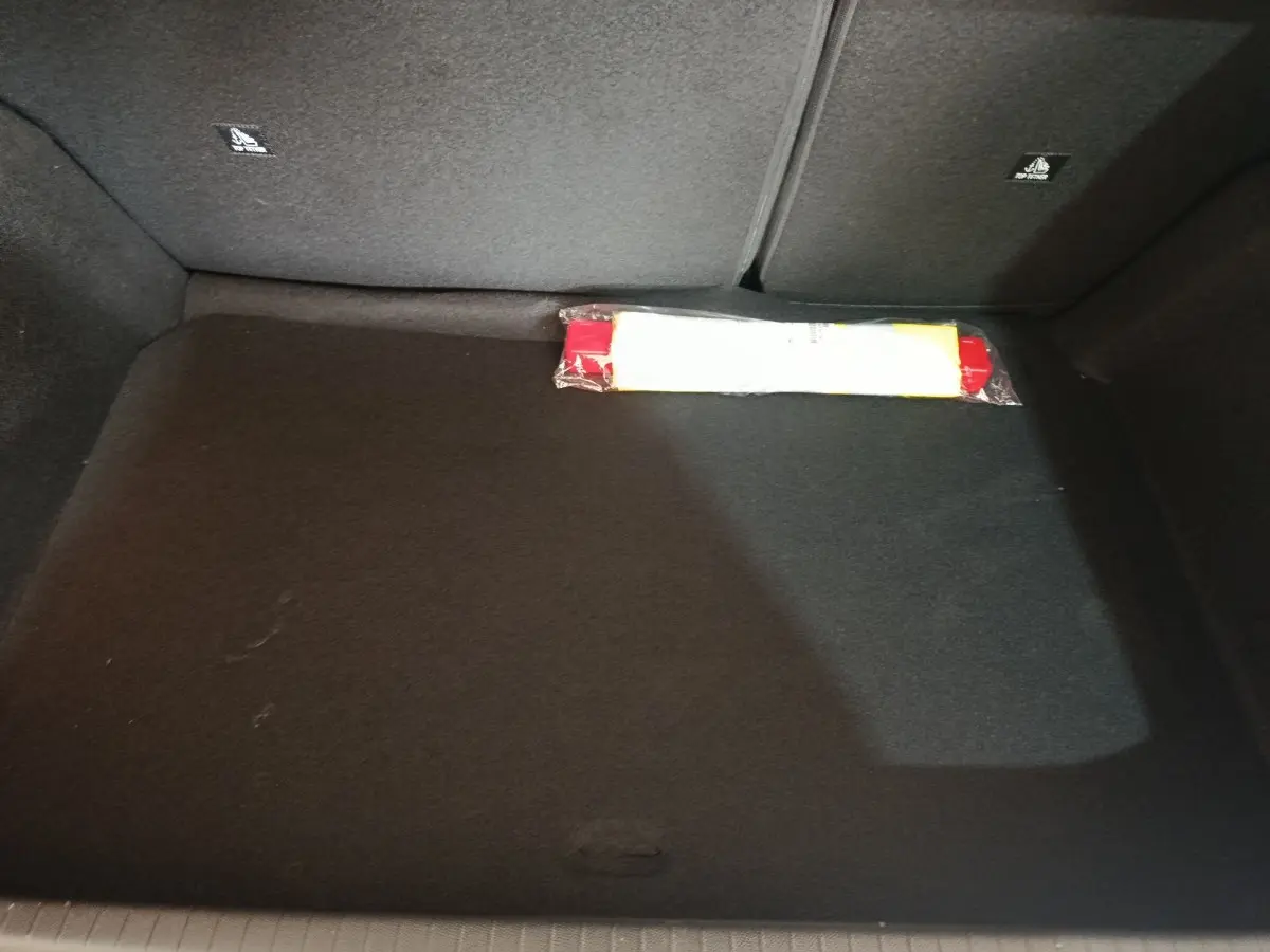 Coffre spacieux de Peugeot 208 Hybrid gris clair, vue intérieure montrant un triangle de signalisation rangé au fond.