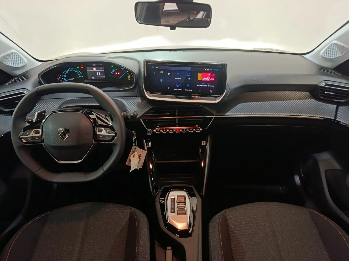 Vue intérieure frontale du tableau de bord et volant cuir noir de la Peugeot 208 Hybrid 100 e-DCS6 Style 2025.