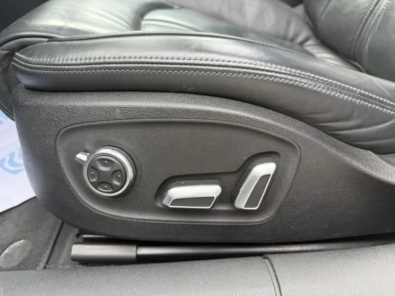 Gros plan sur les commandes électriques du siège en cuir noir de l'Audi A7 Sportback blanc 2018, version Competition Quattro.