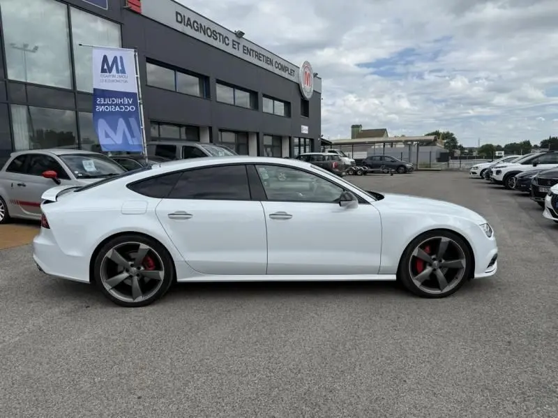 Profil côté gauche d'une Audi A7 Sportback blanche de 2018 avec jantes grises et étriers de frein rouges.