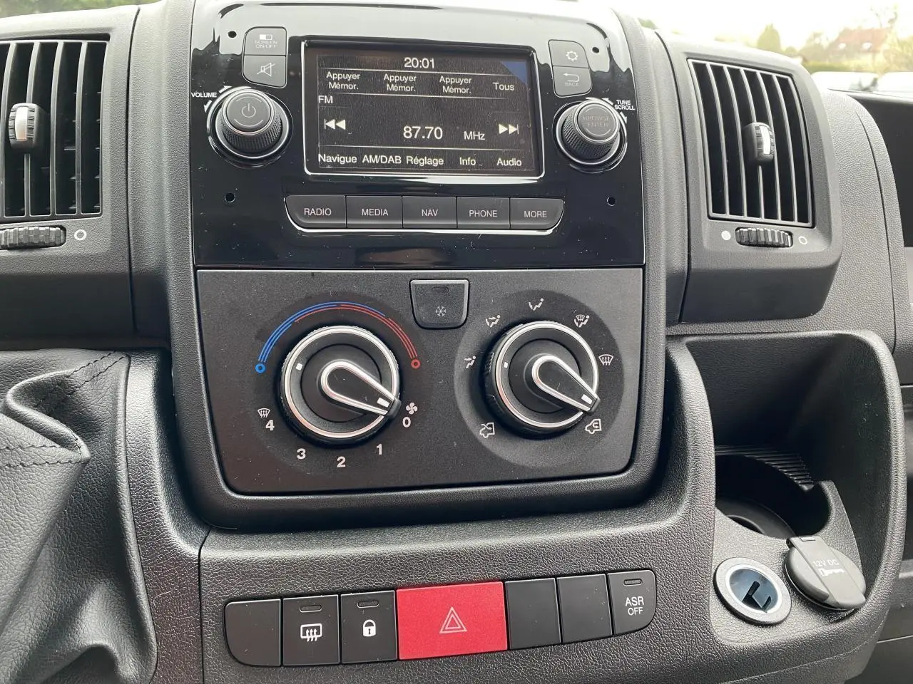 Tableau de bord central de l'Opel Movano Fourgon 2022 avec commandes climatisation, radio DAB et boutons d'alerte visibles.