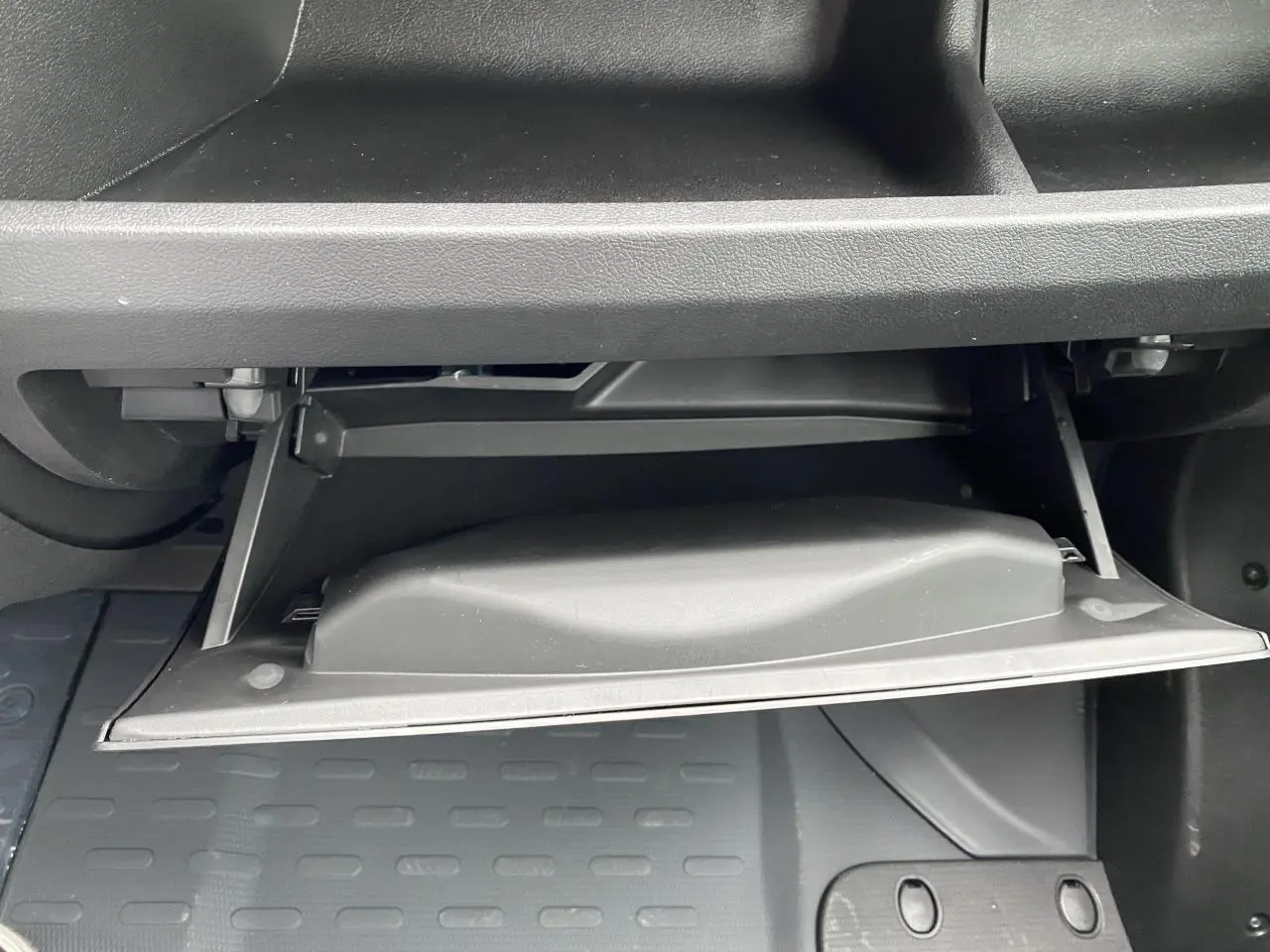 Gros plan sur la boîte à gants ouverte de l'Opel Movano Fourgon blanc, intérieur noir et plancher caoutchouc.