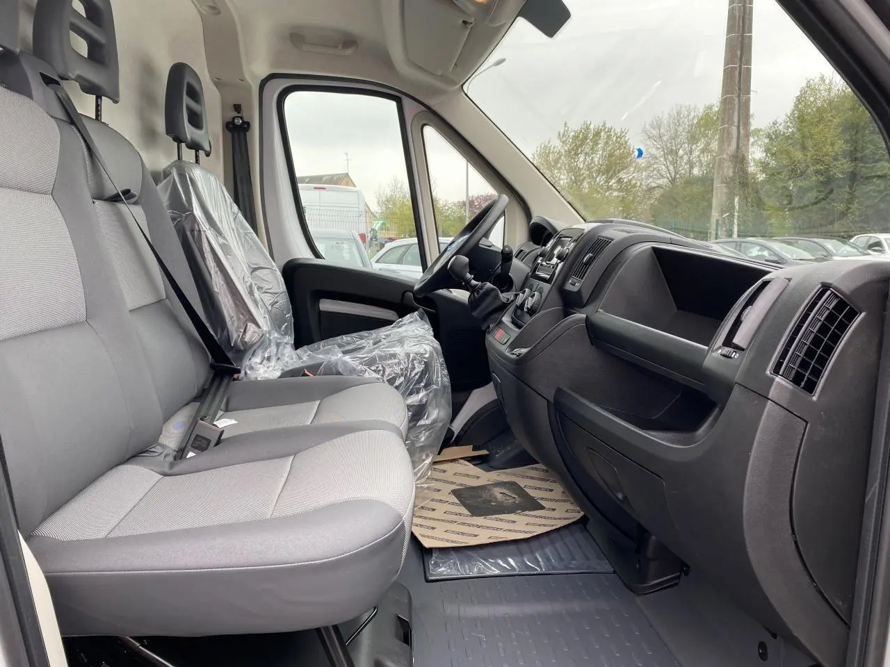 Intérieur côté droit de l'Opel Movano Fourgon blanc 2022, montrant les sièges gris et le tableau de bord noir.