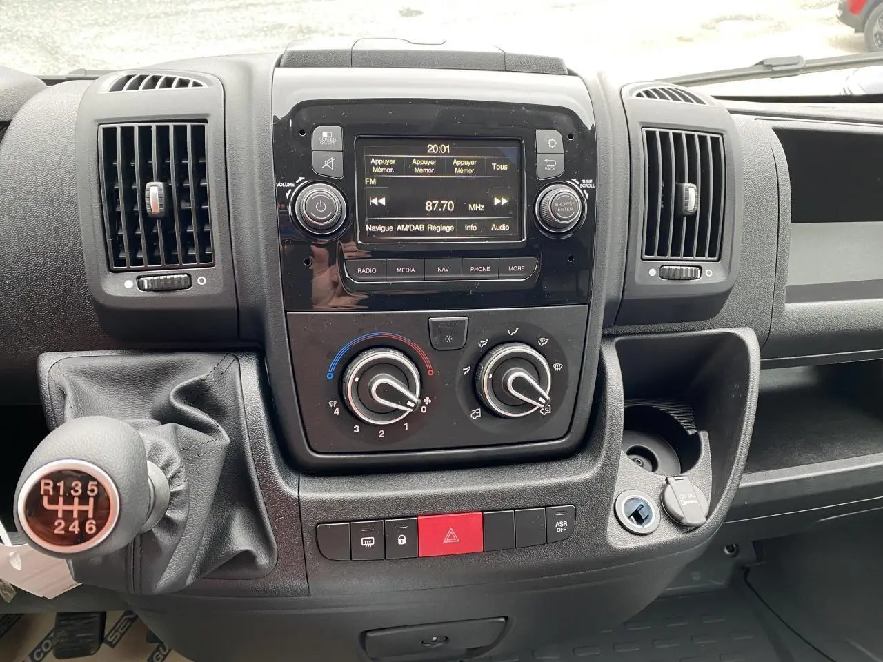 Vue rapprochée du tableau de bord noir de l'Opel Movano Fourgon 2022 avec commandes manuelles et écran multimédia.