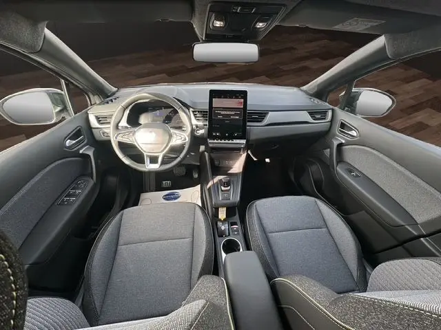 Vue intérieure avant du Renault Captur 2025, tableau de bord moderne avec écran vertical et sièges gris tissu.