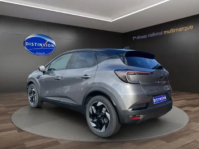 Vue 3/4 arrière du Renault Captur 2025 gris Cassiopée avec toit noir, peinture bi-ton et jantes noires distinctives.