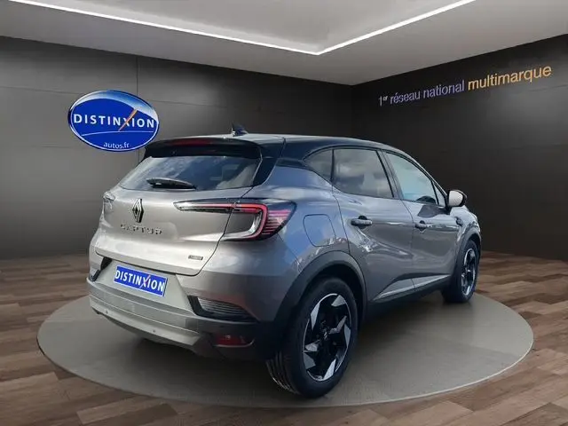 Vue 3/4 arrière droite du Renault Captur 2025 gris Cassiopée avec toit noir et jantes noires distinctives.