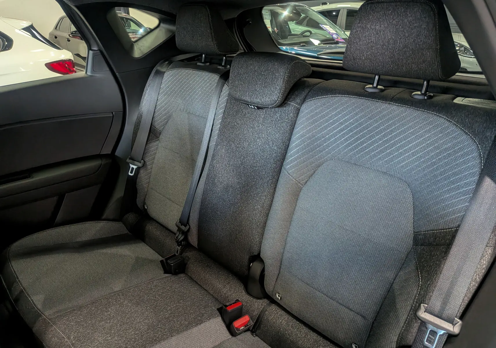 Vue intérieure des sièges arrière en tissu gris du Renault Captur 2025, avec ceintures de sécurité visibles.