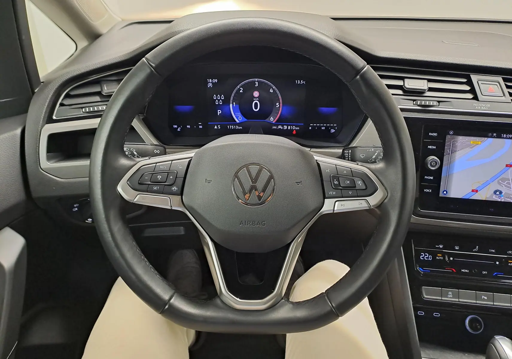 Vue intérieure centrée sur le volant noir du Volkswagen Touran 2024 avec tableau de bord numérique et écran tactile.