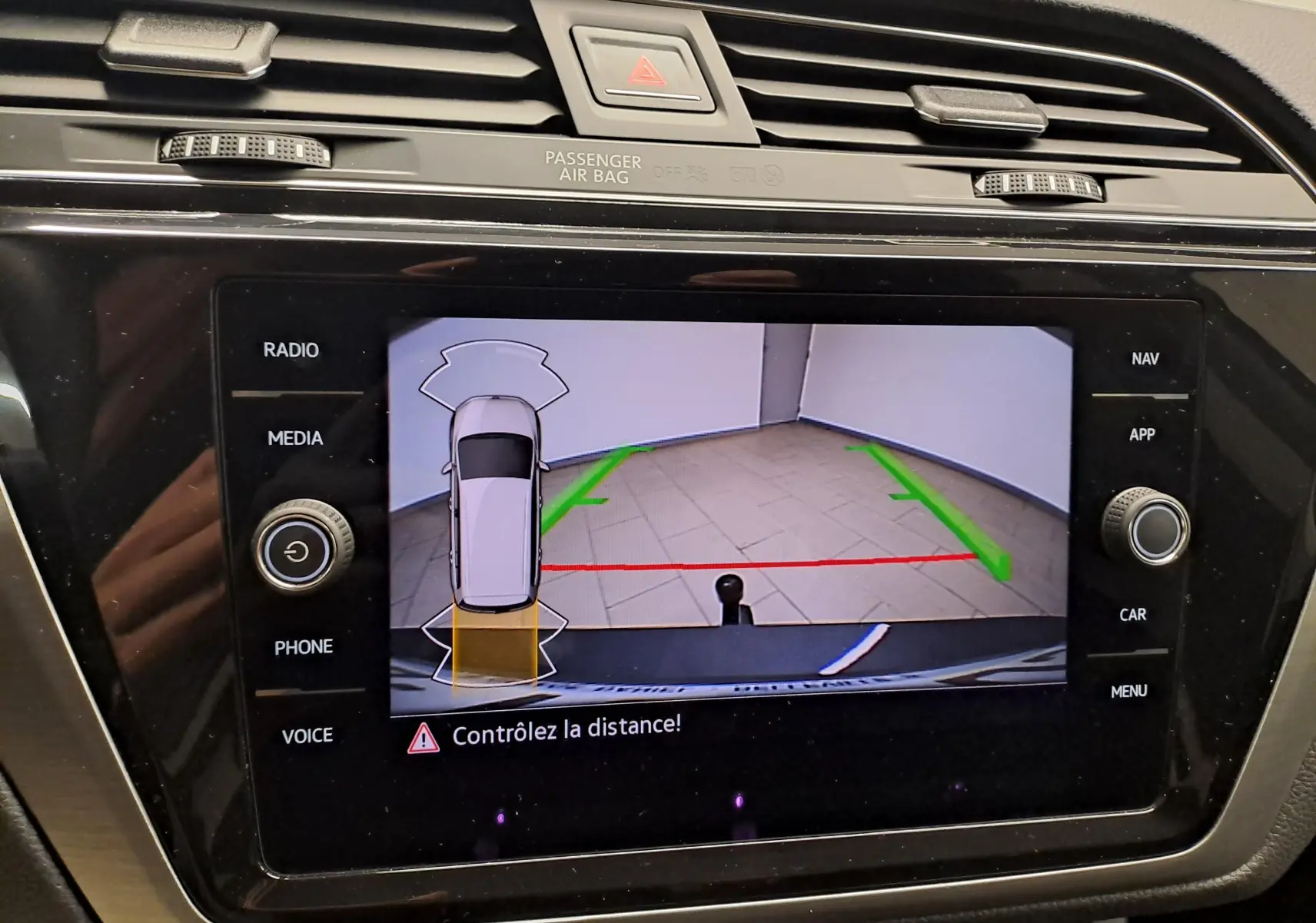 Écran de caméra de recul du Volkswagen Touran 2024 montrant l'attelage et les lignes de guidage vertes et rouges.