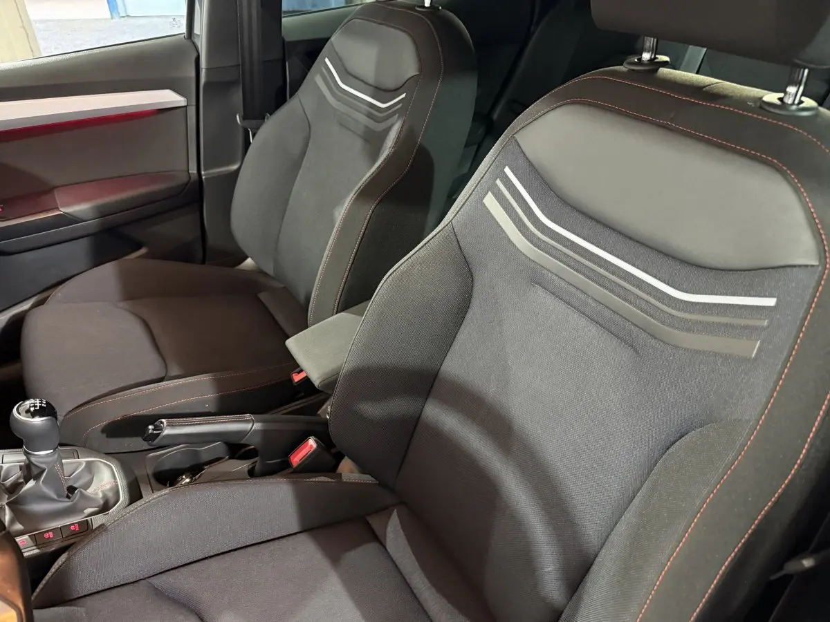 Vue rapprochée des sièges avant noirs avec surpiqûres rouges et motifs gris dans l’habitacle d’une SEAT Ibiza 2024.