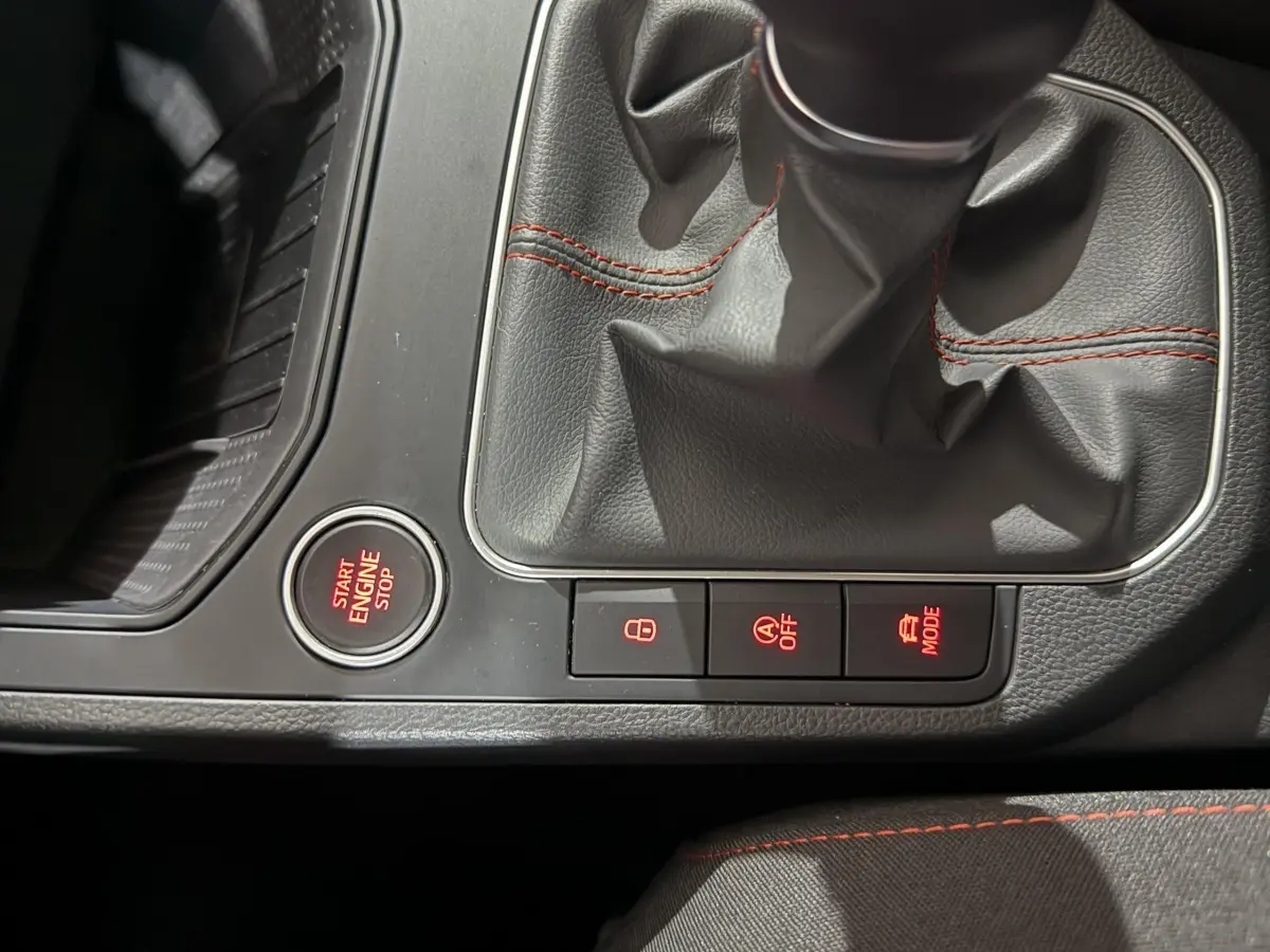 Gros plan sur la console centrale de la SEAT IBIZA 1.0 TSI 110 FR 2024 avec levier de vitesses et boutons lumineux rouges.