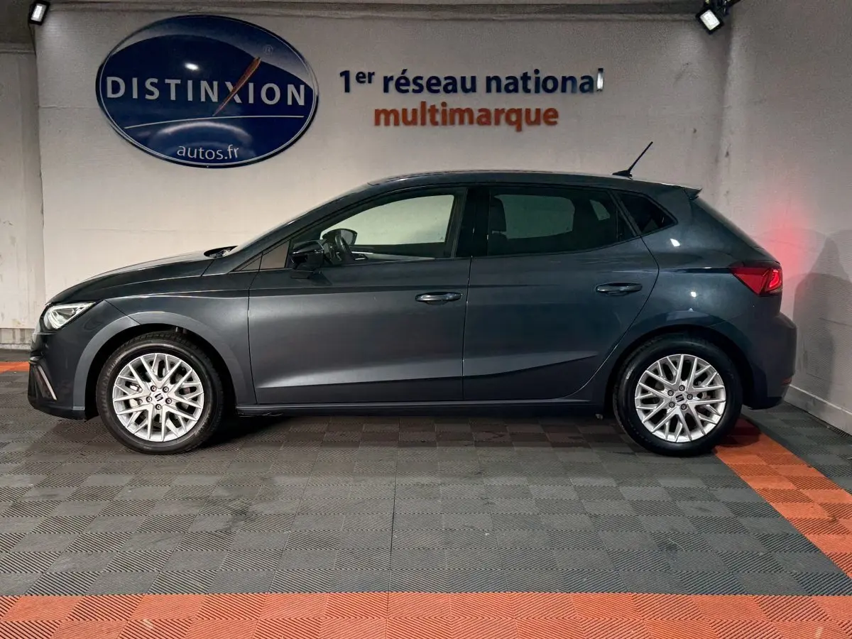 Profil droit d'une SEAT Ibiza gris foncé 2024 garée en intérieur avec jantes alliage et feux arrière allumés.