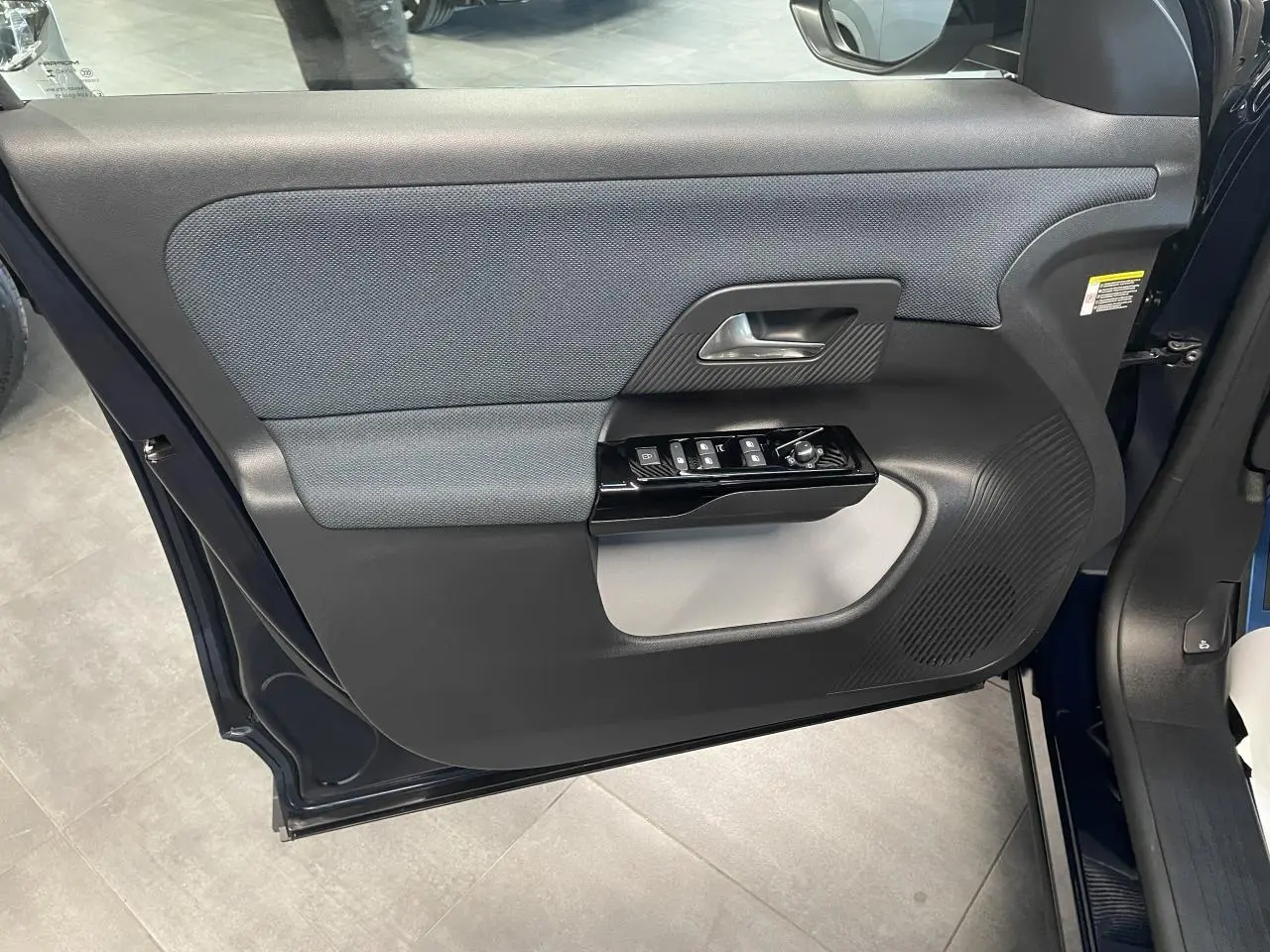 Porte avant gauche ouverte du Citroën C5 Aircross Bleu Azul, montrant les commandes électriques et le haut-parleur intégré.