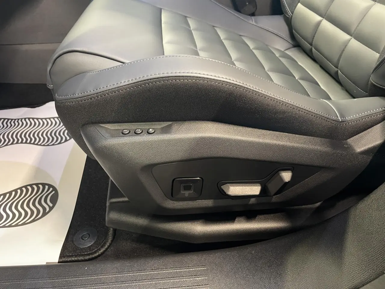 Gros plan sur le siège conducteur gris du Citroën C5 Aircross 1.2i Hybride avec commandes électriques latérales.