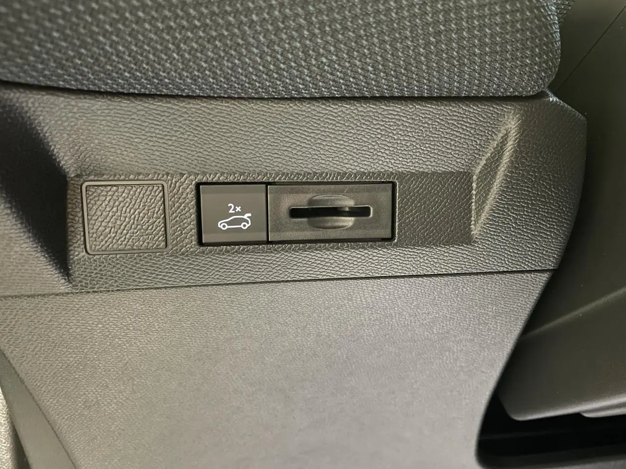 Détail du bouton d'ouverture du hayon électrique sur la planche de bord noire du Citroën C5 Aircross Bleu Azul.