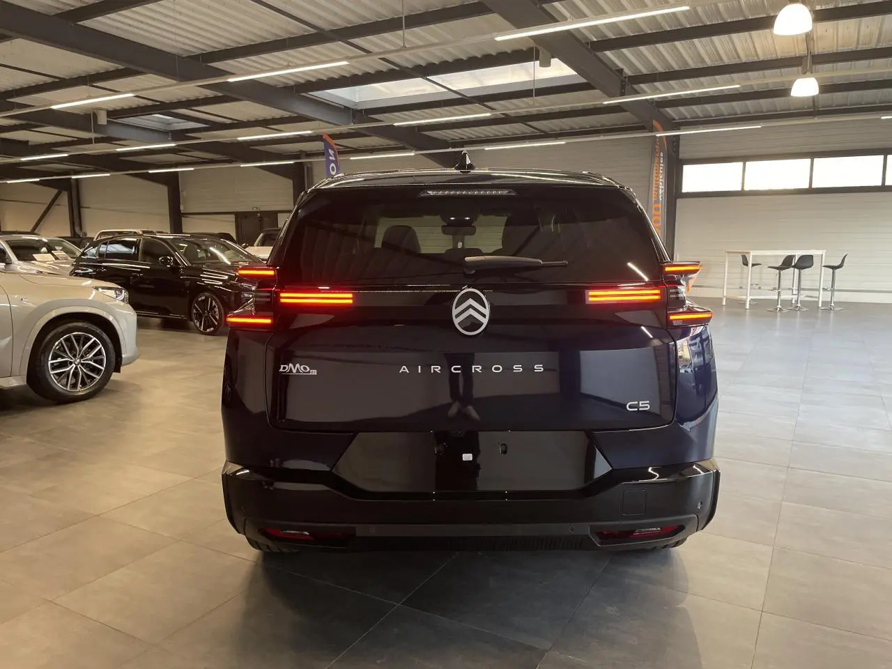 Vue arrière d'un Citroën C5 Aircross bleu Azul avec feux arrière LED allumés dans un showroom.