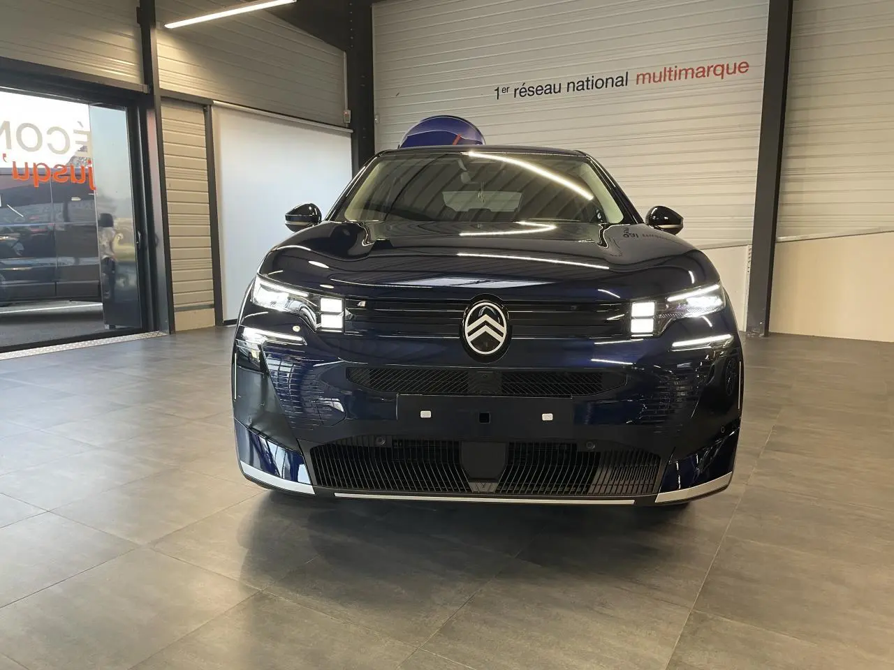 Vue de face d'un Citroën C5 Aircross 2026 bleu Azul avec calandre noire brillante et feux LED Matrix allumés.