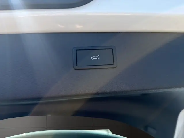 Bouton d'ouverture électrique du coffre sur la garniture intérieure d'un CUPRA Formentor blanc, vue rapprochée.