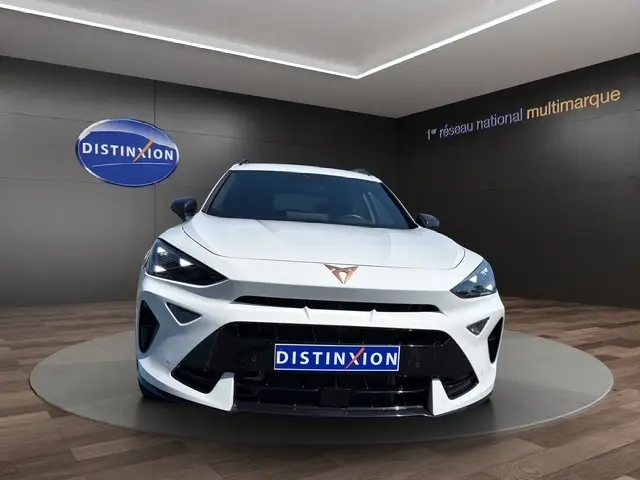 Vue avant d'un CUPRA Formentor blanc 2025 avec logo cuivré et calandre noire dans un showroom moderne.