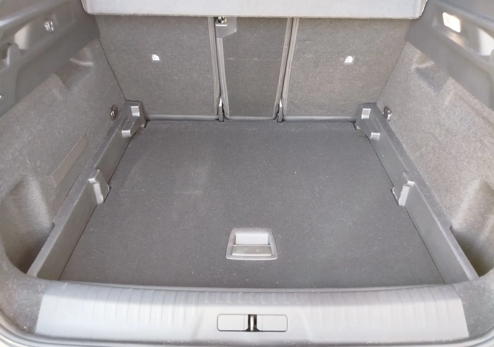 Coffre spacieux du Peugeot 3008 2024 vu de l'intérieur, revêtement noir et banquette arrière rabattue.