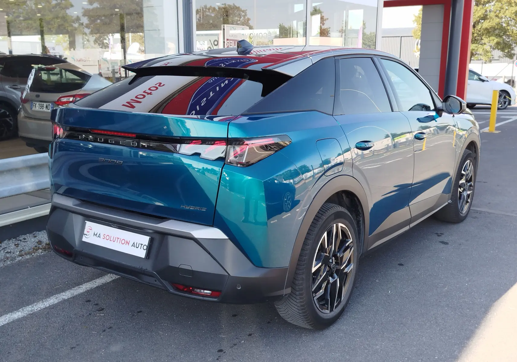 Vue 3/4 arrière droite du Peugeot 3008 1.2 Hybride 136 ch GT bleu Obsession avec toit noir et jantes bi-ton.