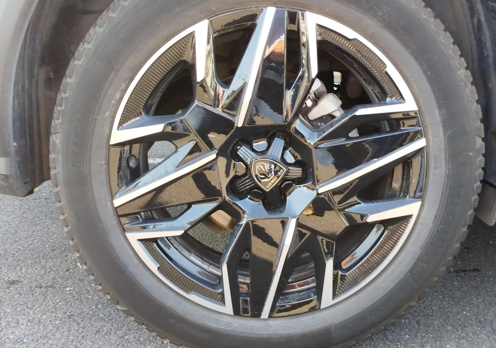 Gros plan sur la jante noire et argentée du Peugeot 3008 1.2 Hybride 136 ch GT, avec logo Lion central visible.