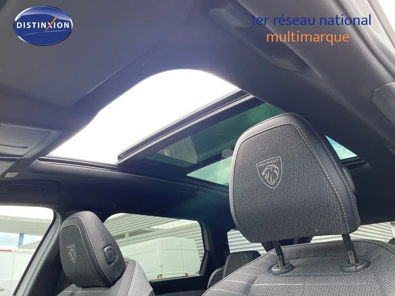 Vue intérieure du Peugeot 5008 Hybrid 136ch GT 2025, sièges avant noirs avec logo Peugeot et toit ouvrant panoramique.